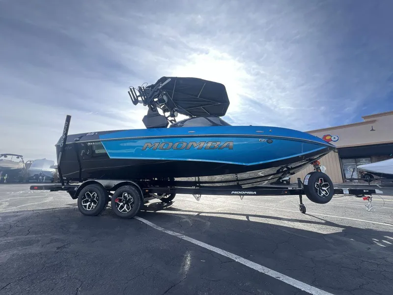 Slide: The Image of 2025 Moomba Mojo boat on trailer, blue and black design, parked outdoors. - 6