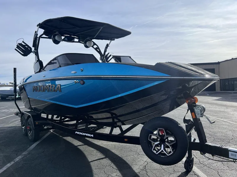 Slide: The Image of 2025 Moomba Mojo boat in blue on a trailer, parked outdoors. - 7