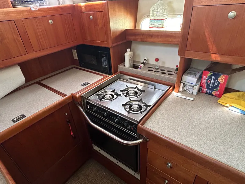 Slide: The Image of 1998 Hunter Passage 450 yacht kitchen with stove, microwave, and wooden cabinetry. - 21