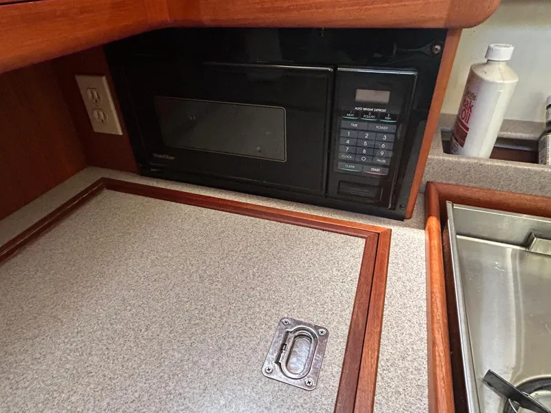 Slide: The Image of 1998 Hunter Passage 450 yacht kitchen with microwave, countertop, and sink. - 24
