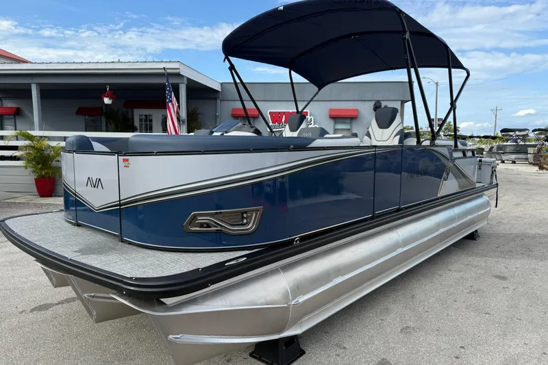 The Image of 2025 Avalon LSZ Quad Lounger 24' Tri Toon High Performance boat with canopy, parked outdoors. - 25