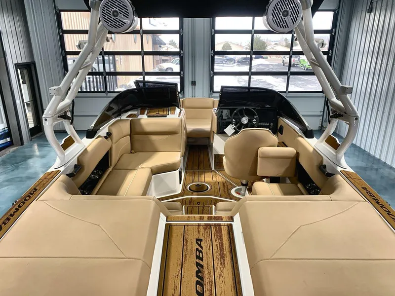 Slide: The Image of 2025 Moomba Mondo boat interior with beige seating and modern dashboard in a showroom. - 9
