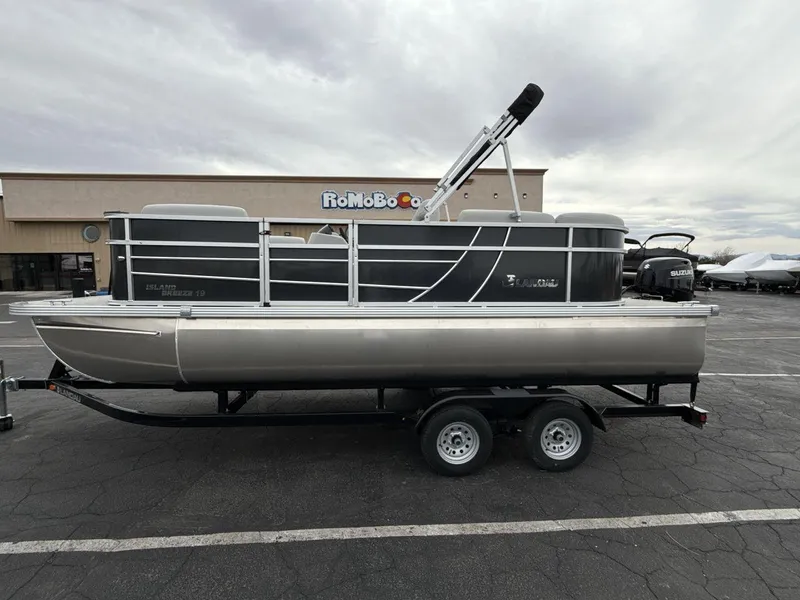 Slide: The Image of 2025 Landau Island Breeze 19 C pontoon boat on trailer in parking lot. - 2