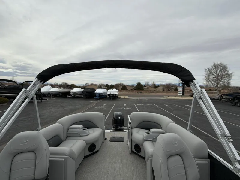 Slide: The Image of 2025 Landau Island Breeze 19 C pontoon boat with gray seating and canopy in a parking lot. - 21