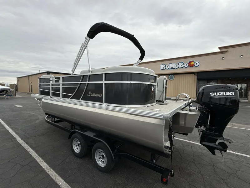 Slide: The Image of 2025 Landau Island Breeze 19 C pontoon boat with Suzuki outboard motor on trailer. - 3