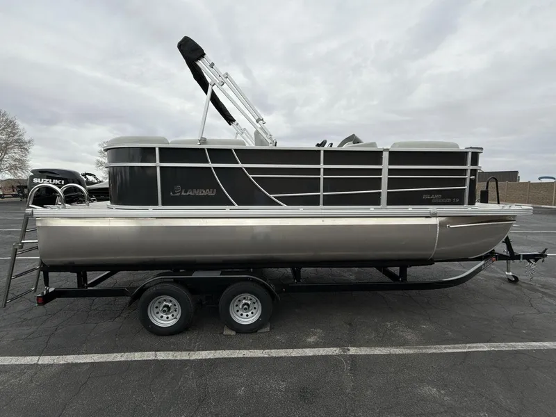Slide: The Image of 2025 Landau Island Breeze 19 C pontoon boat on trailer, overcast sky background. - 6
