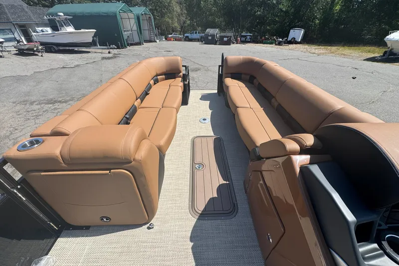 Slide: The Image of 2025 Regency 250 LE3 Sport pontoon boat with tan leather seating, docked outdoors. - 4