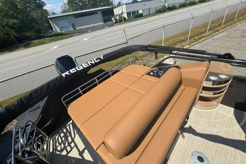 Slide: The Image of 2025 Regency 250 LE3 Sport boat with tan seating and cup holders, parked near a road. - 5