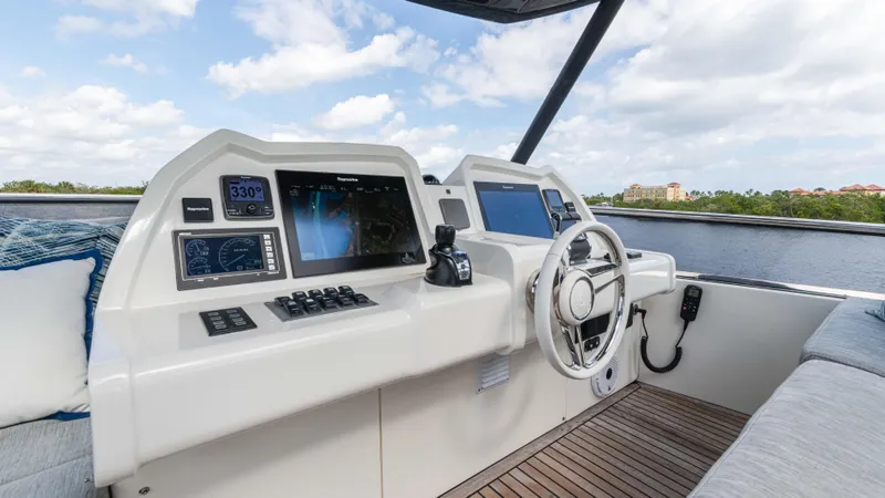 Slide: The Image of 2016 Monte Carlo Yachts MCY 65 helm with modern navigation equipment and scenic water view. - 15