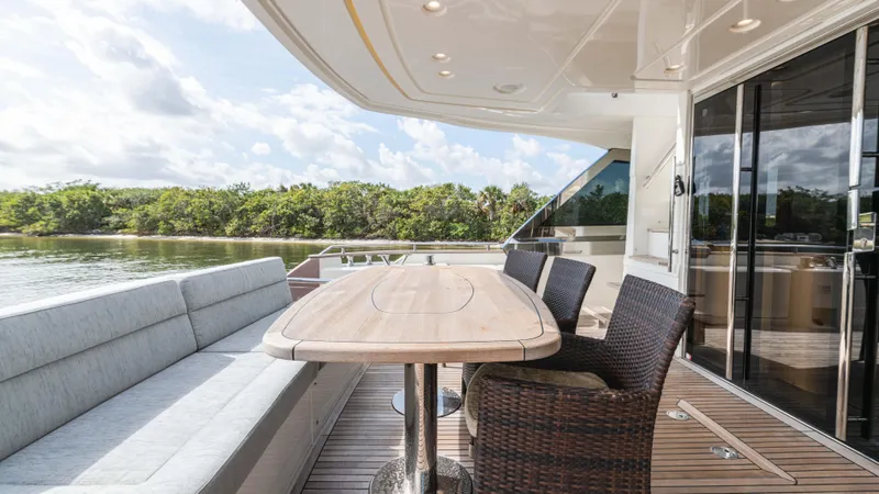 Slide: The Image of Luxury outdoor seating on 2016 Monte Carlo Yachts MCY 65, featuring elegant wicker chairs and wooden table. - 22