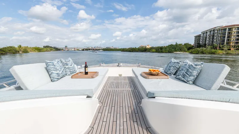 Slide: The Image of Luxurious Monte Carlo Yachts MCY 65 deck with cushions, wine, and fruit, overlooking serene waters. - 26
