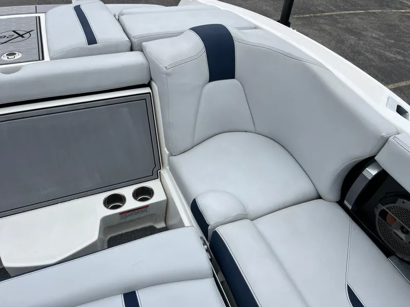 Slide: The Image of 2019 MasterCraft X26 boat interior with white and blue seating, cup holders, and speaker. - 12