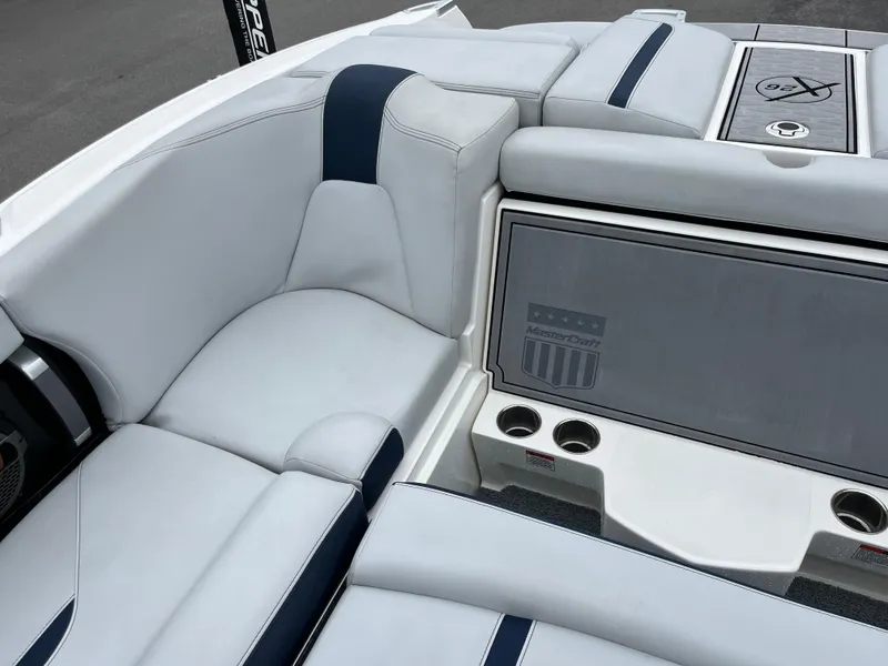 Slide: The Image of 2019 MasterCraft X26 boat interior with white and navy seating, cup holders, and branded panel. - 13