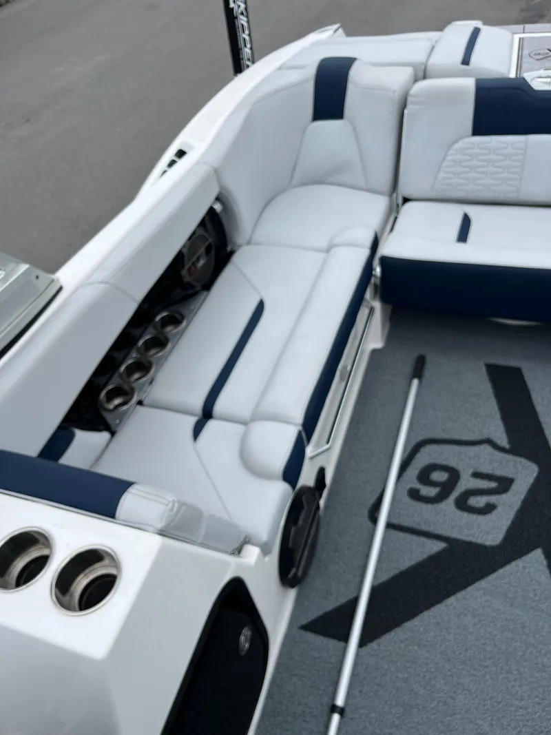 Slide: The Image of 2019 MasterCraft X26 boat interior with white and blue seating and cup holders. - 15