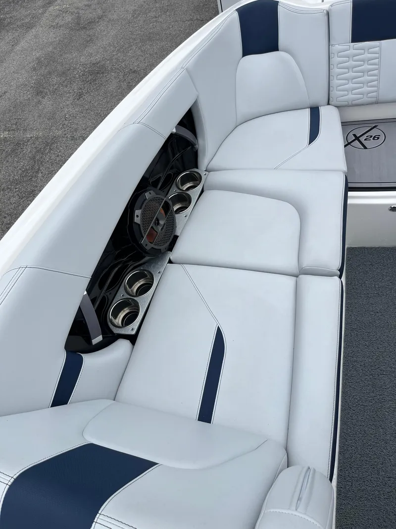 Slide: The Image of 2019 MasterCraft X26 boat interior with white and blue seating and cup holders. - 24