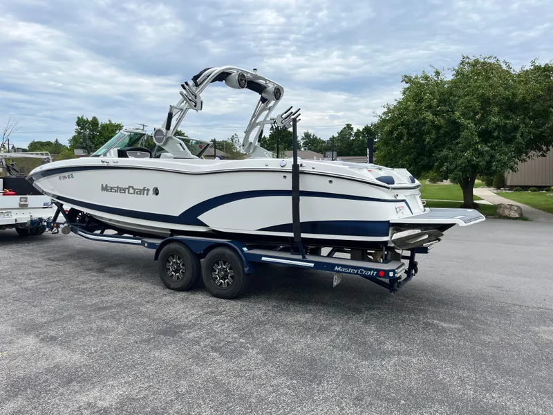 Slide: The Image of 2019 MasterCraft X26 boat on trailer, parked outdoors on a cloudy day. - 29