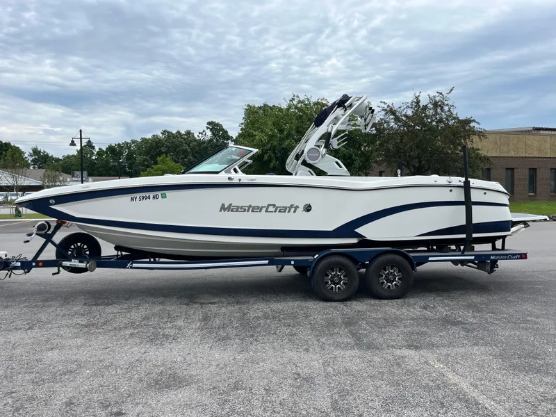 Slide: The Image of 2019 MasterCraft X26 boat on trailer, parked outdoors, showcasing sleek design and modern features. - 30