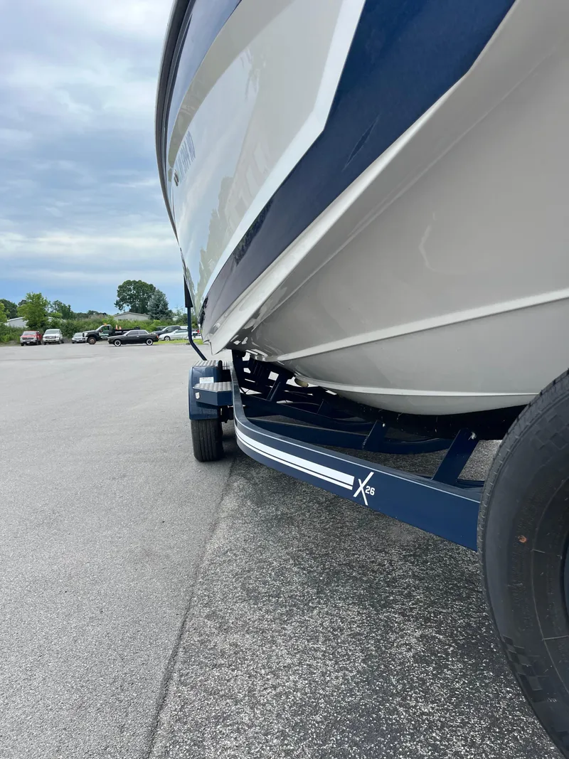 Slide: The Image of 2019 MasterCraft X26 boat on trailer, parked on asphalt under cloudy sky. - 32