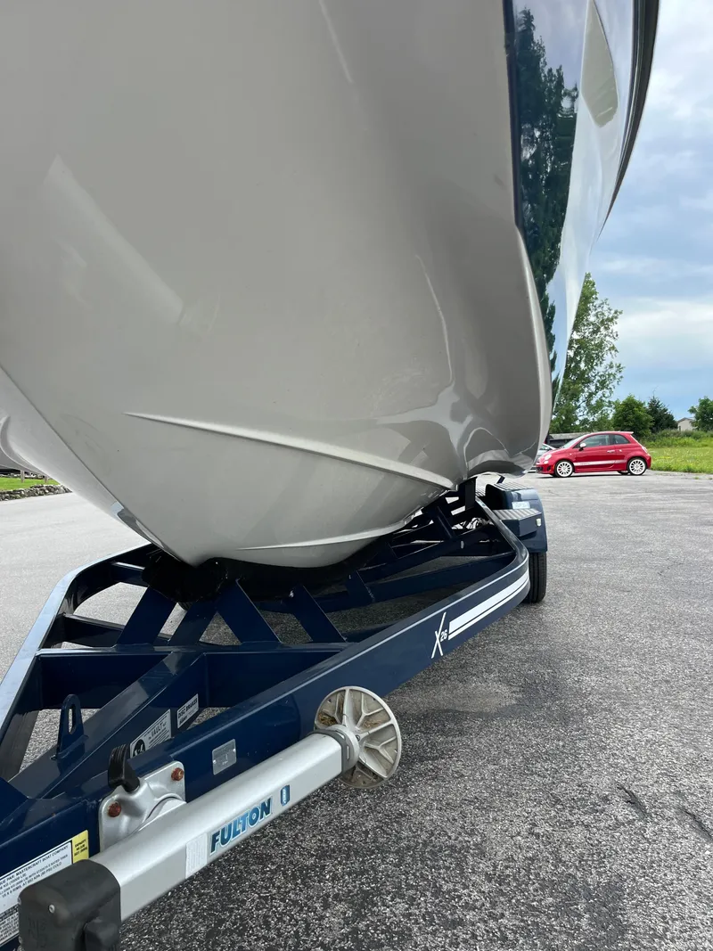 Slide: The Image of 2019 MasterCraft X26 boat on trailer, parked on asphalt with a car in the background. - 33
