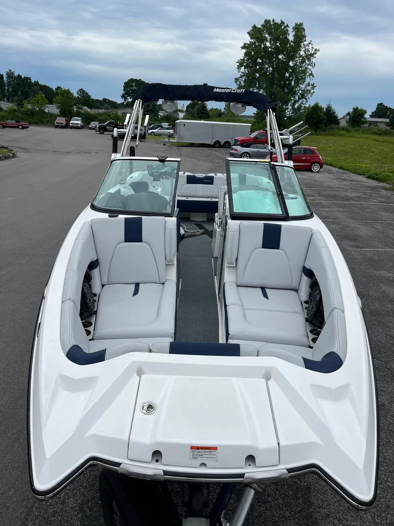 Slide: The Image of 2019 MasterCraft X26 boat with white and blue seating, parked outdoors. - 34