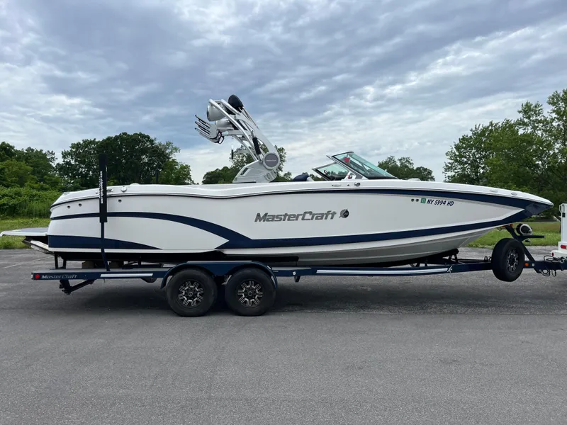 Slide: The Image of 2019 MasterCraft X26 boat on trailer, parked outdoors under cloudy sky. - 4