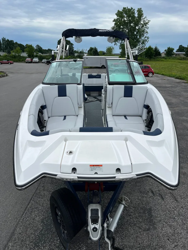 Slide: The Image of 2019 MasterCraft X26 boat with white and blue seating, parked on a trailer. - 6