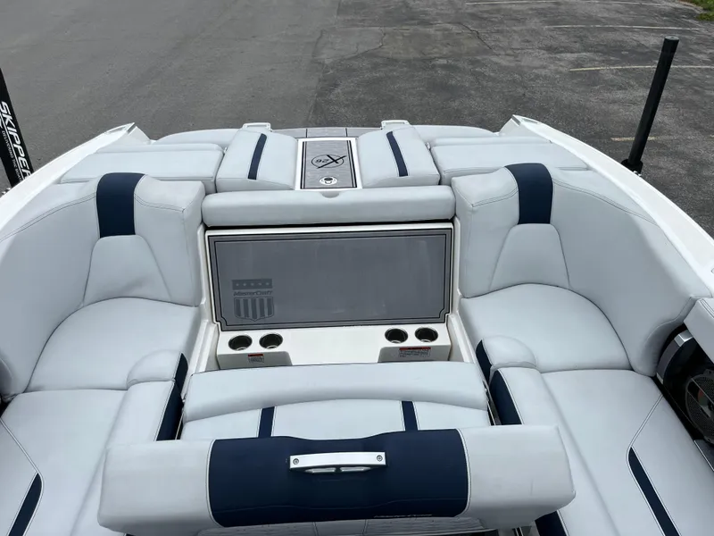 Slide: The Image of 2019 MasterCraft X26 boat interior with white and navy seating, cup holders, and storage compartment. - 7
