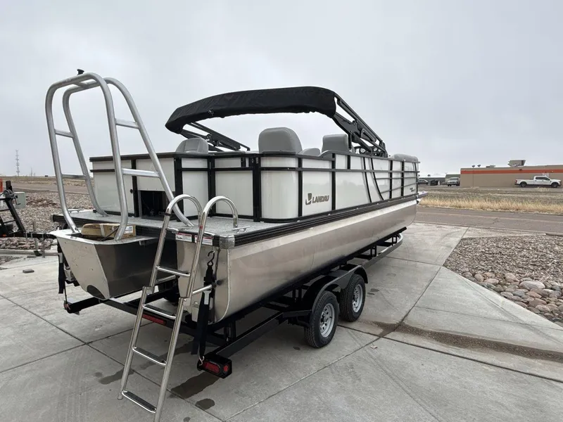 Slide: The Image of 2025 Landau ISLAND BREEZE 23 pontoon boat on trailer, featuring sleek design and ladder. - 5