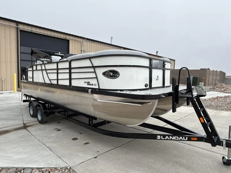 Slide: The Image of 2025 Landau ISLAND BREEZE 23 pontoon boat on trailer outside warehouse. - 7