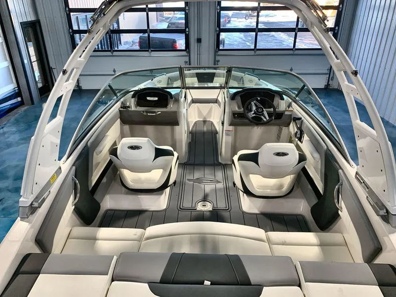 Slide: The Image of 2025 Chaparral 21 SSi boat interior with modern seating and steering wheel in showroom. - 9
