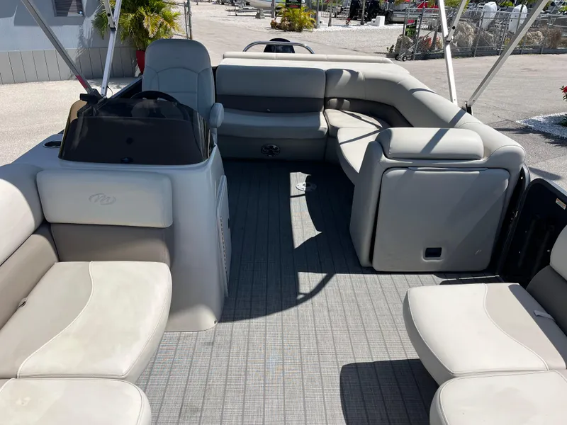 Slide: The Image of 2020 Manitou 20 Aurora LE Standard pontoon boat interior with beige seating and helm. - 14
