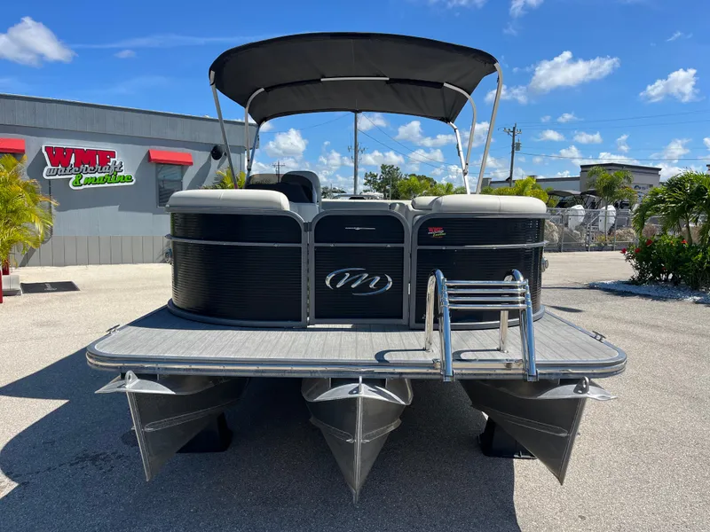 Slide: The Image of 2020 Manitou 20 Aurora LE Standard pontoon boat with canopy, parked outdoors. - 2