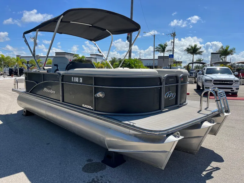 Slide: The Image of 2020 Manitou 20 Aurora LE Standard pontoon boat with canopy, parked outdoors. - 3
