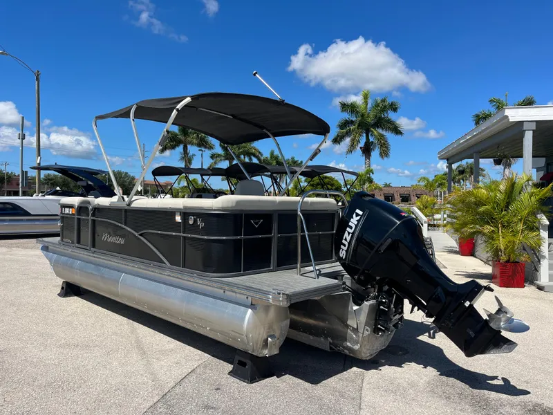 Slide: The Image of 2020 Manitou 20 Aurora LE Standard pontoon boat with Suzuki outboard motor, parked outdoors. - 7