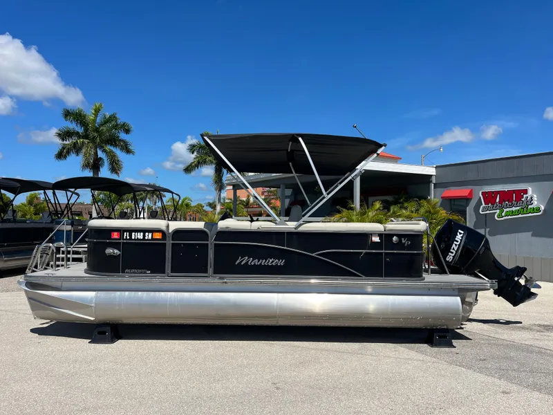 Slide: The Image of 2020 Manitou 20 Aurora LE Standard pontoon boat with Suzuki outboard motor, parked outdoors. - 8