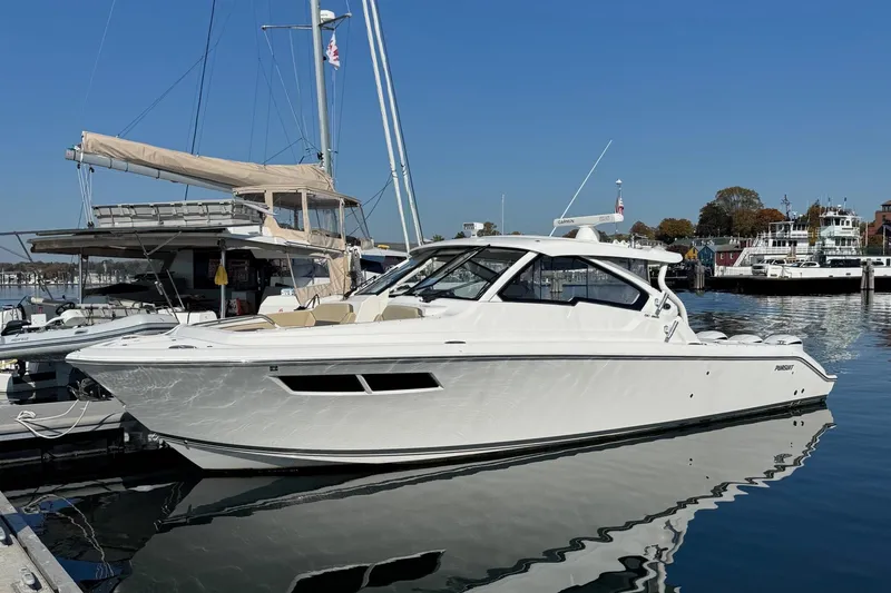 The Image of 2019 Pursuit DC 365 Dual Console boat docked in a marina under clear blue skies. - 0