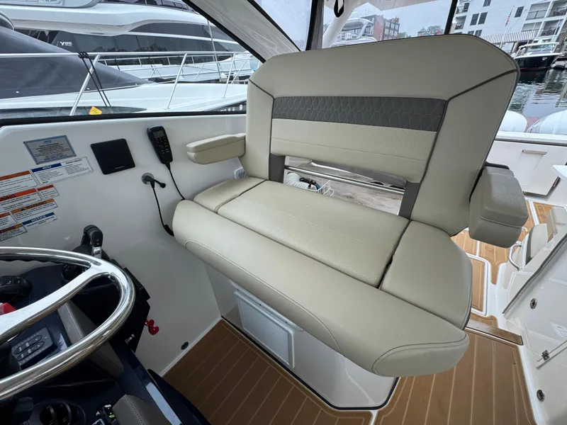 Slide: The Image of 2019 Pursuit DC 365 Dual Console boat interior with beige seating and control panel. - 22