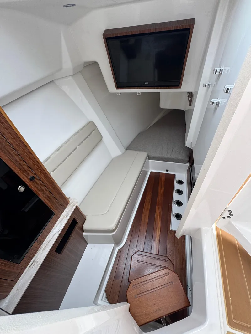 Slide: The Image of 2019 Pursuit DC 365 Dual Console cabin with TV, seating, and wooden flooring. - 25