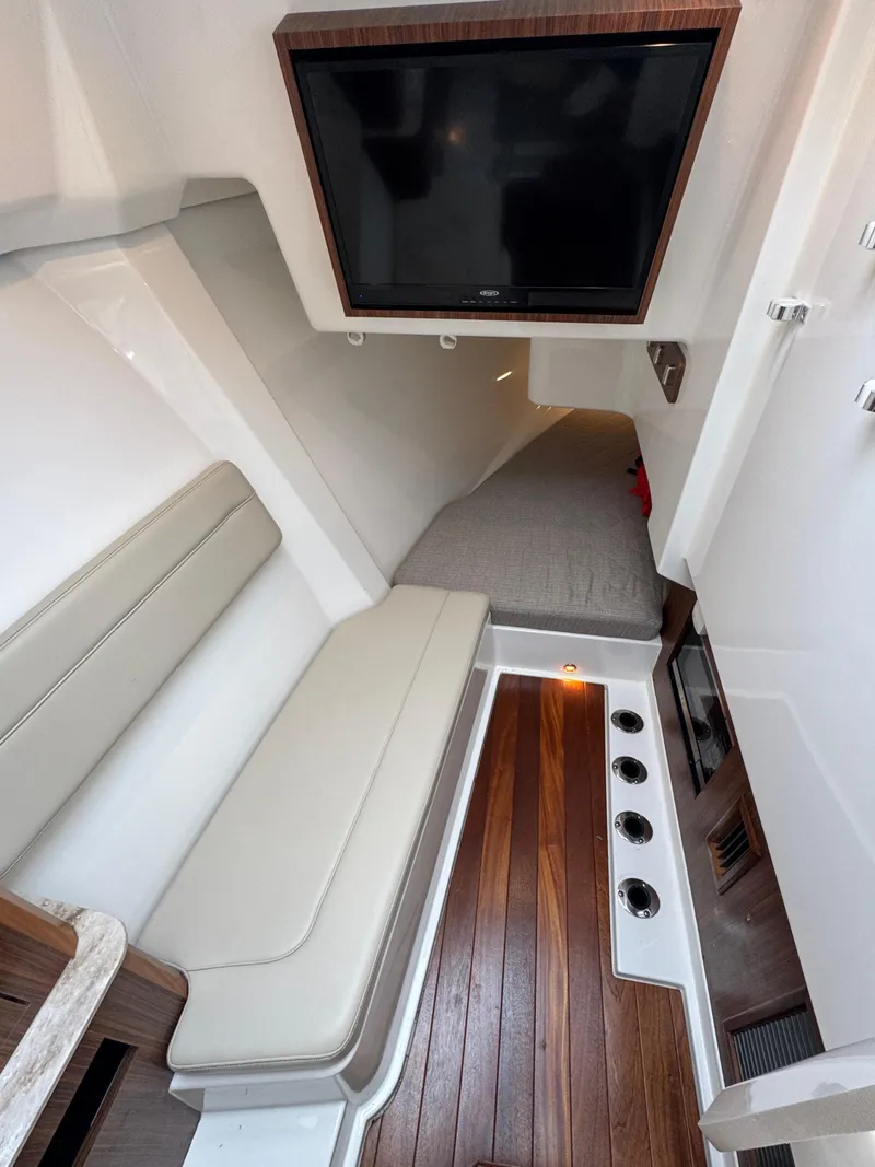 Slide: The Image of 2019 Pursuit DC 365 Dual Console cabin with TV, seating, and wood flooring. - 28