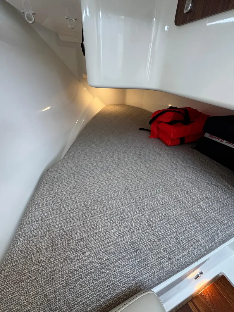 Slide: The Image of 2019 Pursuit DC 365 Dual Console interior cabin with carpet and life jackets. - 29