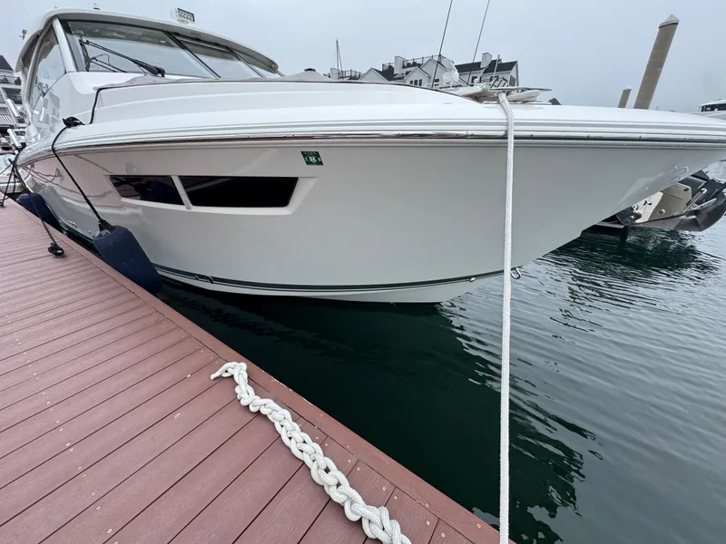 Slide: The Image of 2019 Pursuit DC 365 Dual Console boat docked at marina, side view. - 3