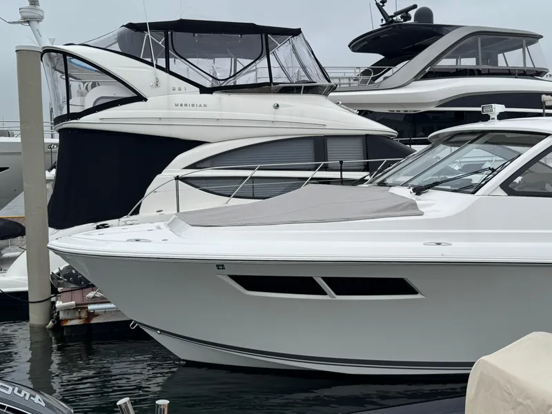 Slide: The Image of 2019 Pursuit DC 365 Dual Console boat docked alongside other luxury yachts. - 4
