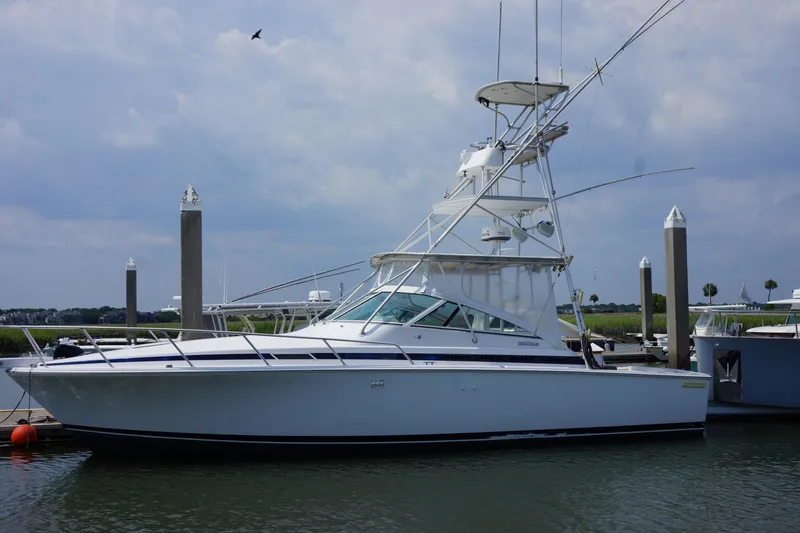 Slide: The Image of 1997 Bertram 36 Moppie yacht docked at marina under cloudy sky. - 1