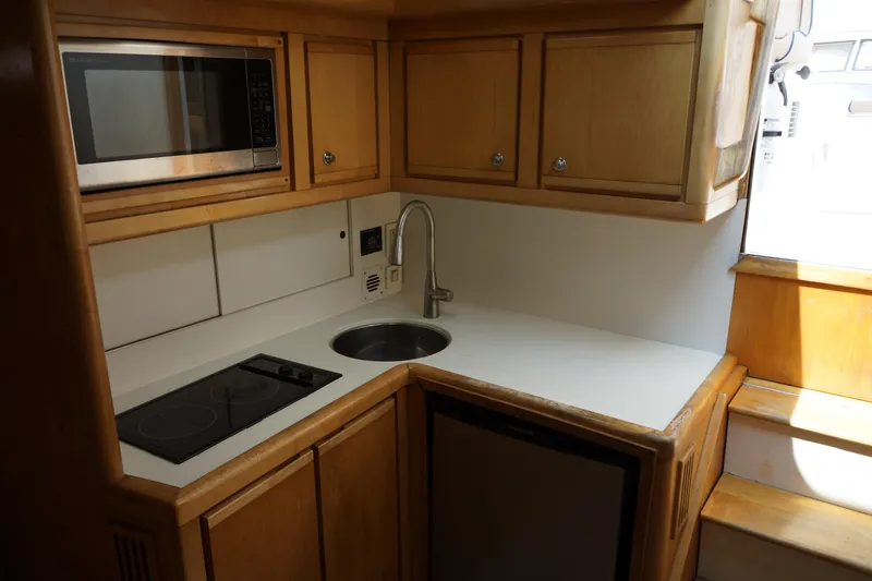 Slide: The Image of Compact kitchen in a 1997 Bertram 36 Moppie boat with microwave, sink, and stove. - 16