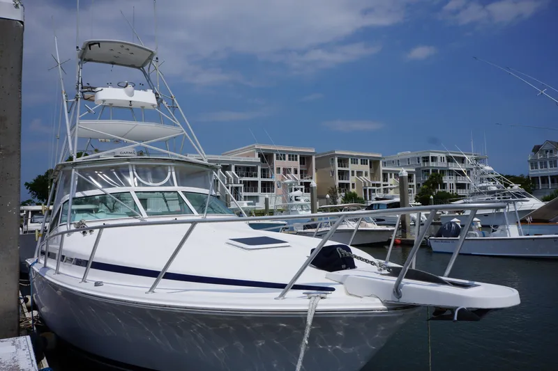 Slide: The Image of 1997 Bertram 36 Moppie yacht docked at marina with waterfront buildings. - 2