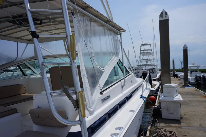 Slide: The Image of 1997 Bertram 36 Moppie docked at marina, featuring sleek design and fishing equipment. - 5