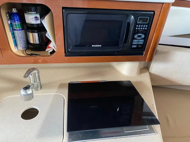 Slide: The Image of 2008 Sea Ray 270 Amberjack kitchen area with microwave, sink, and storage. - 14
