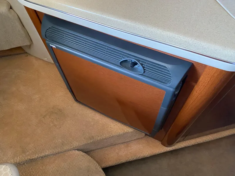 Slide: The Image of 2008 Sea Ray 270 Amberjack cabin interior with compact refrigerator and beige carpet. - 16