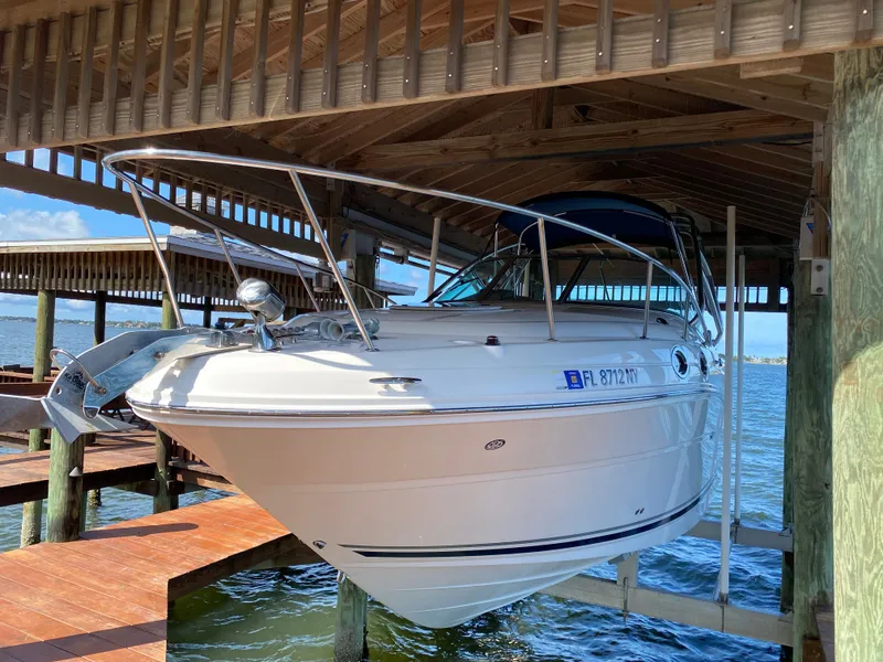 Slide: The Image of 2008 Sea Ray 270 Amberjack boat docked under a wooden shelter by the water. - 2