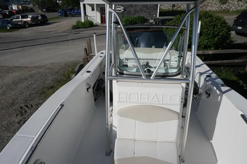 Slide: The Image of 2012 Robalo R200 Center Console boat with white seating and console, parked outdoors. - 19